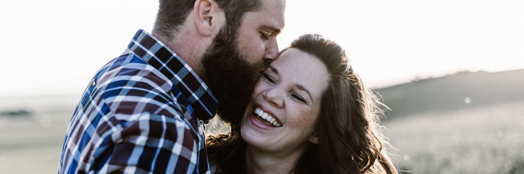 A man kissing his wife on a vancouver beach