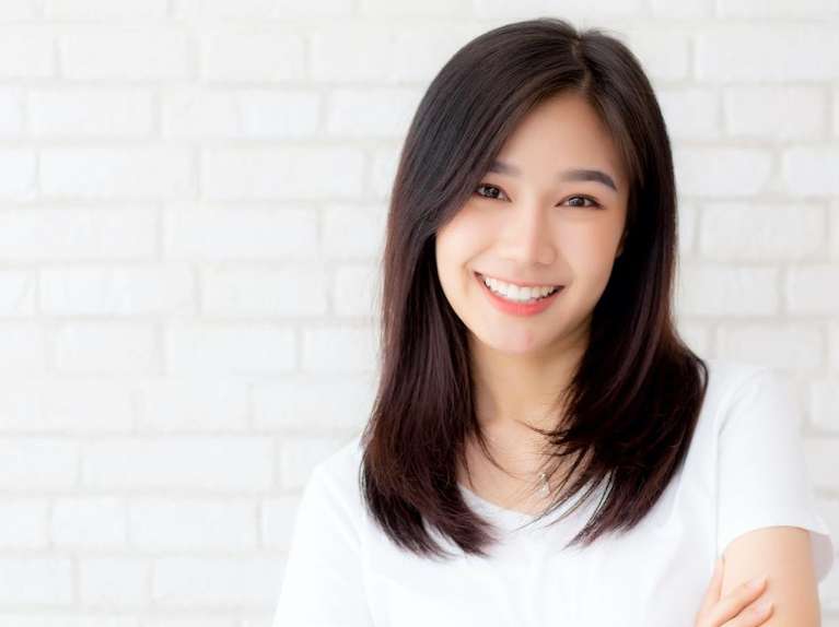 A woman smiling against a white wall