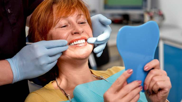A woman looking at her new dental implants | dental implants Vancouver BC