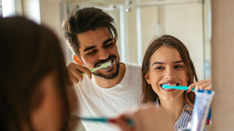 A couple brushing their teeth in the mirror