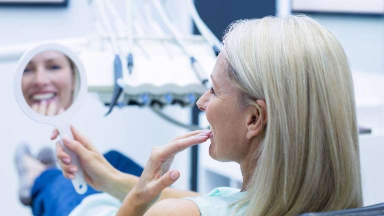 A woman looking at her new porcelain veneers | veneers Vancouver BC