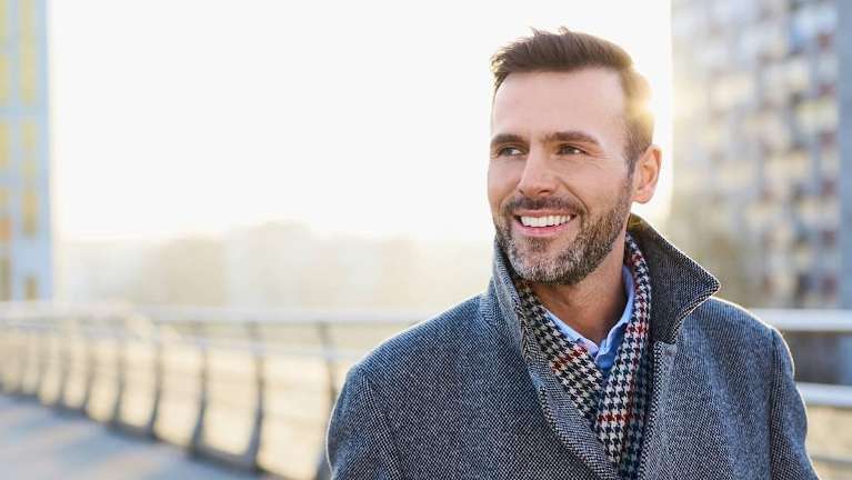 A smiling man walking on a bridge
