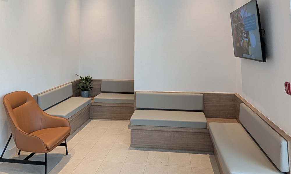 Stylish patient waiting area with deep blue velvet chairs, textured white walls, and a self-serve coffee station.