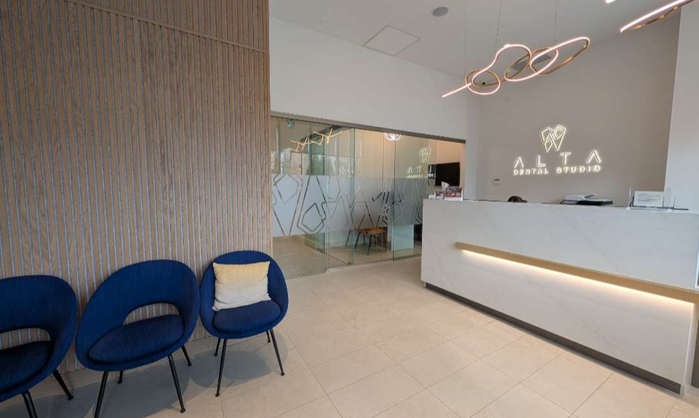 Sleek, modern white reception desk with warm under-counter lighting and elegant globe pendant lights at the entrance.